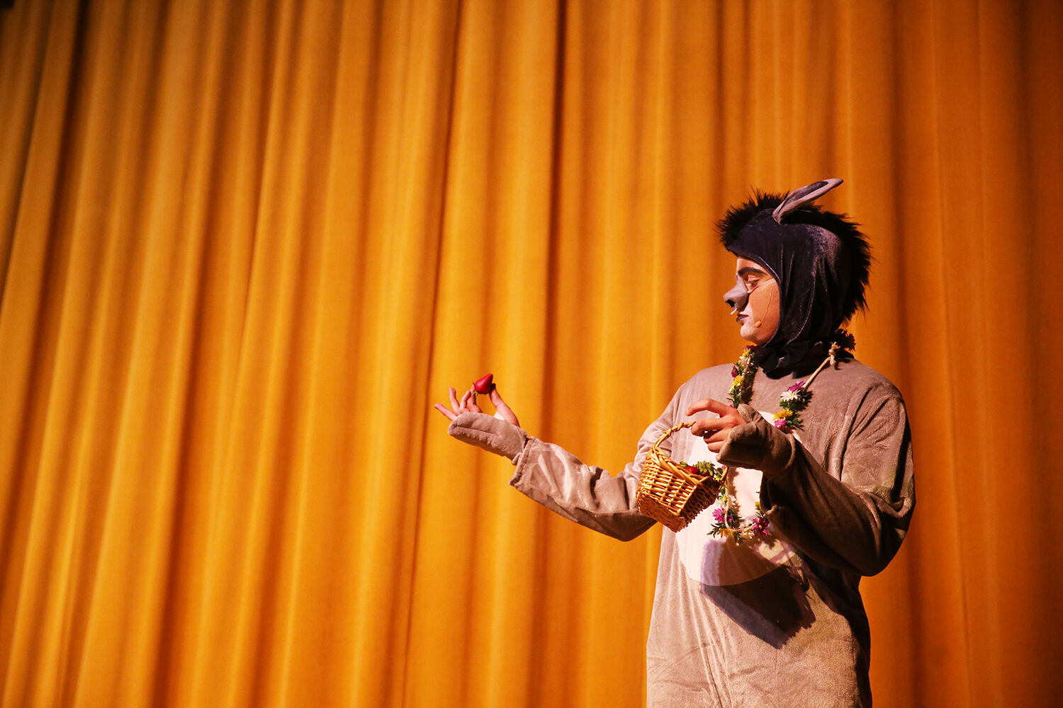 Donkey, played by Fischer Kirven, looks at a strawberry in confusion